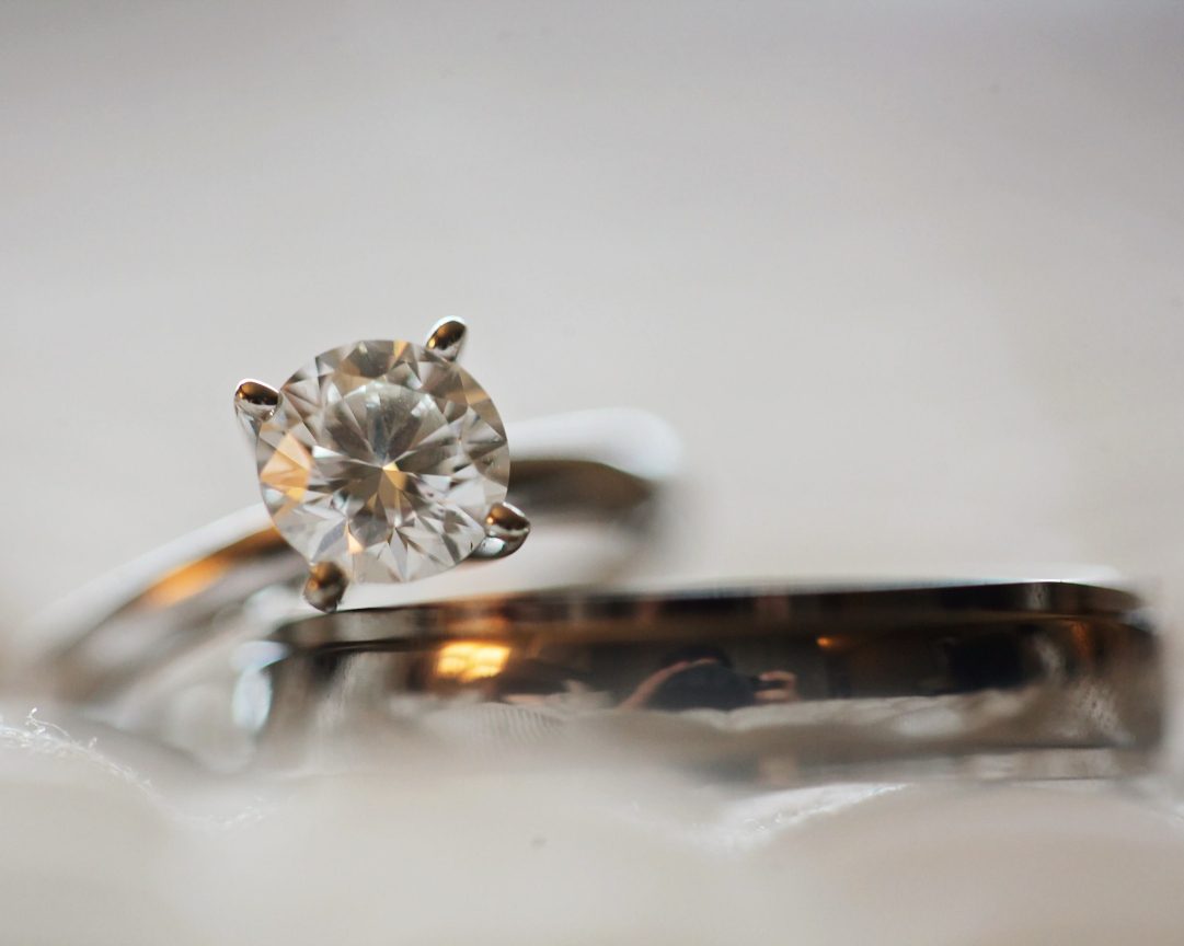 Macro shot of a brilliant-cut solitaire diamond engagement ring with a sleek silver band on a soft surface – ideal jewelry and loan