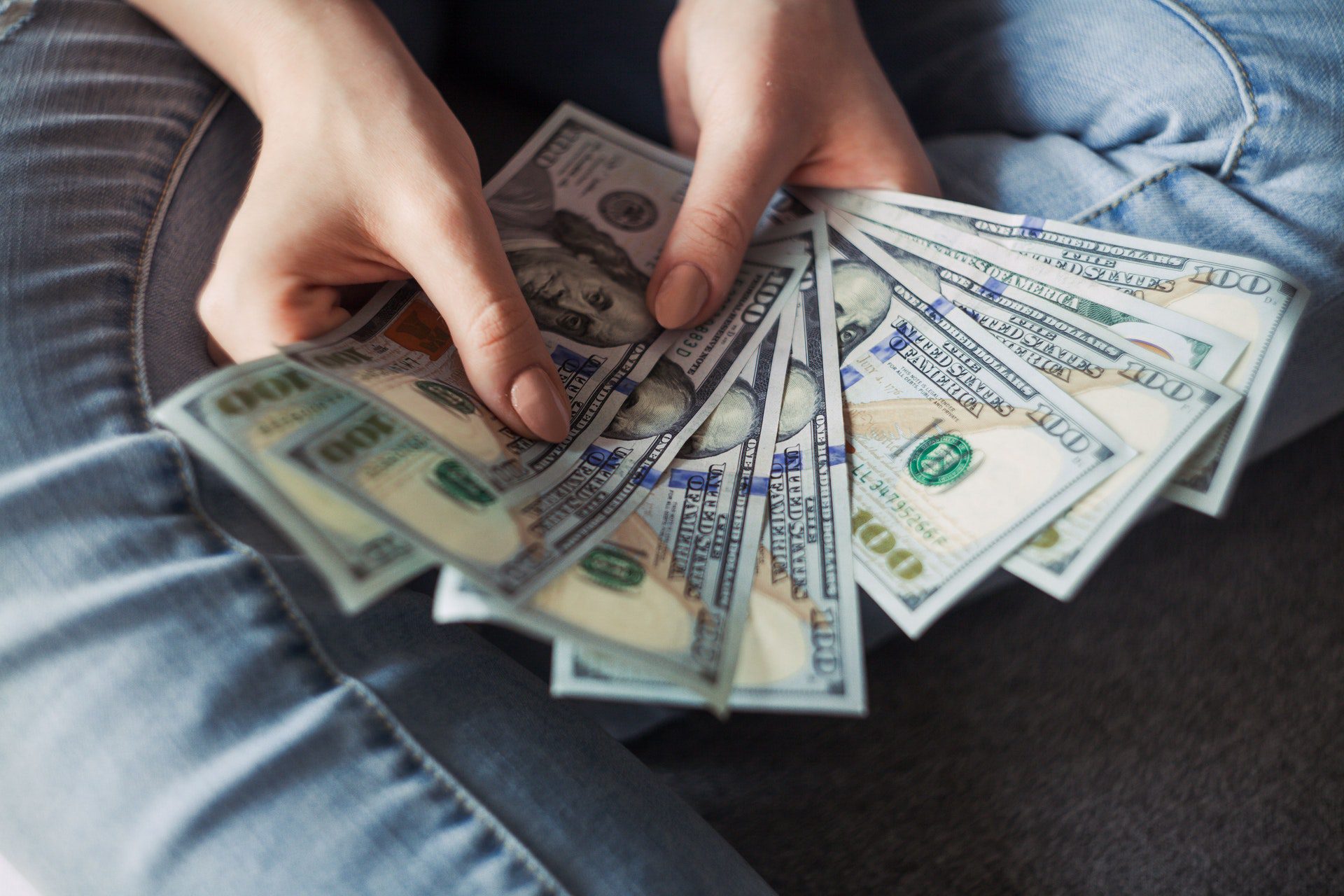 Person holding a fan of hundred dollar bills after receiving a pawn loan