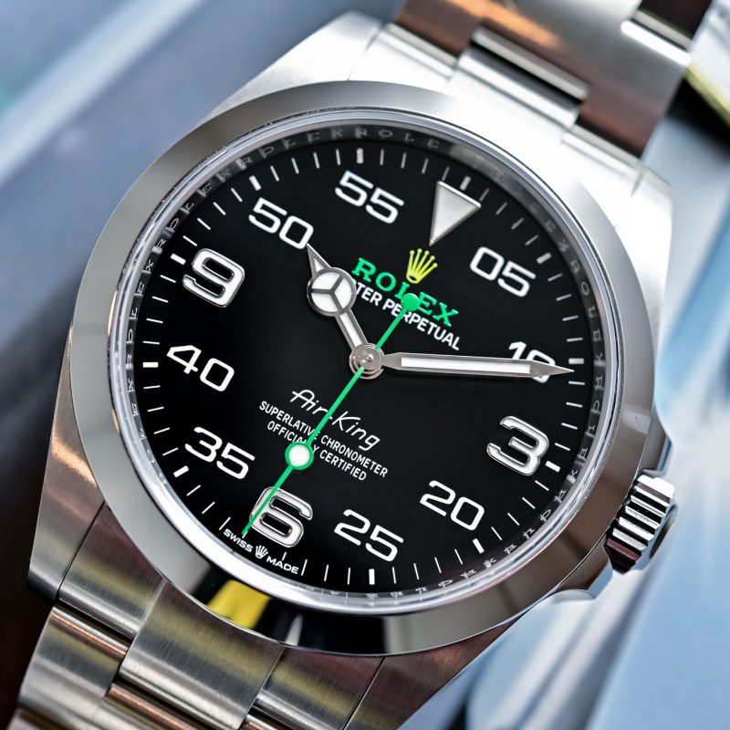 Luxury Rolex watch with black dial and silver band displayed on a magazine