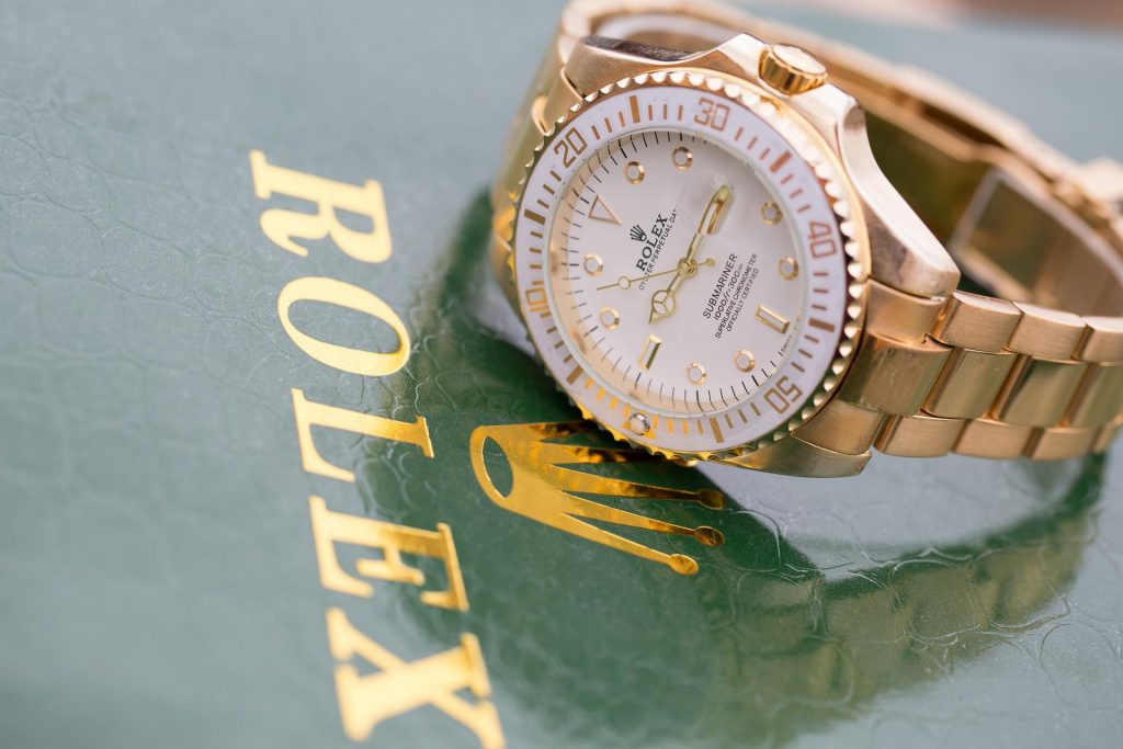 gold rolex watch sitting on green rolex box