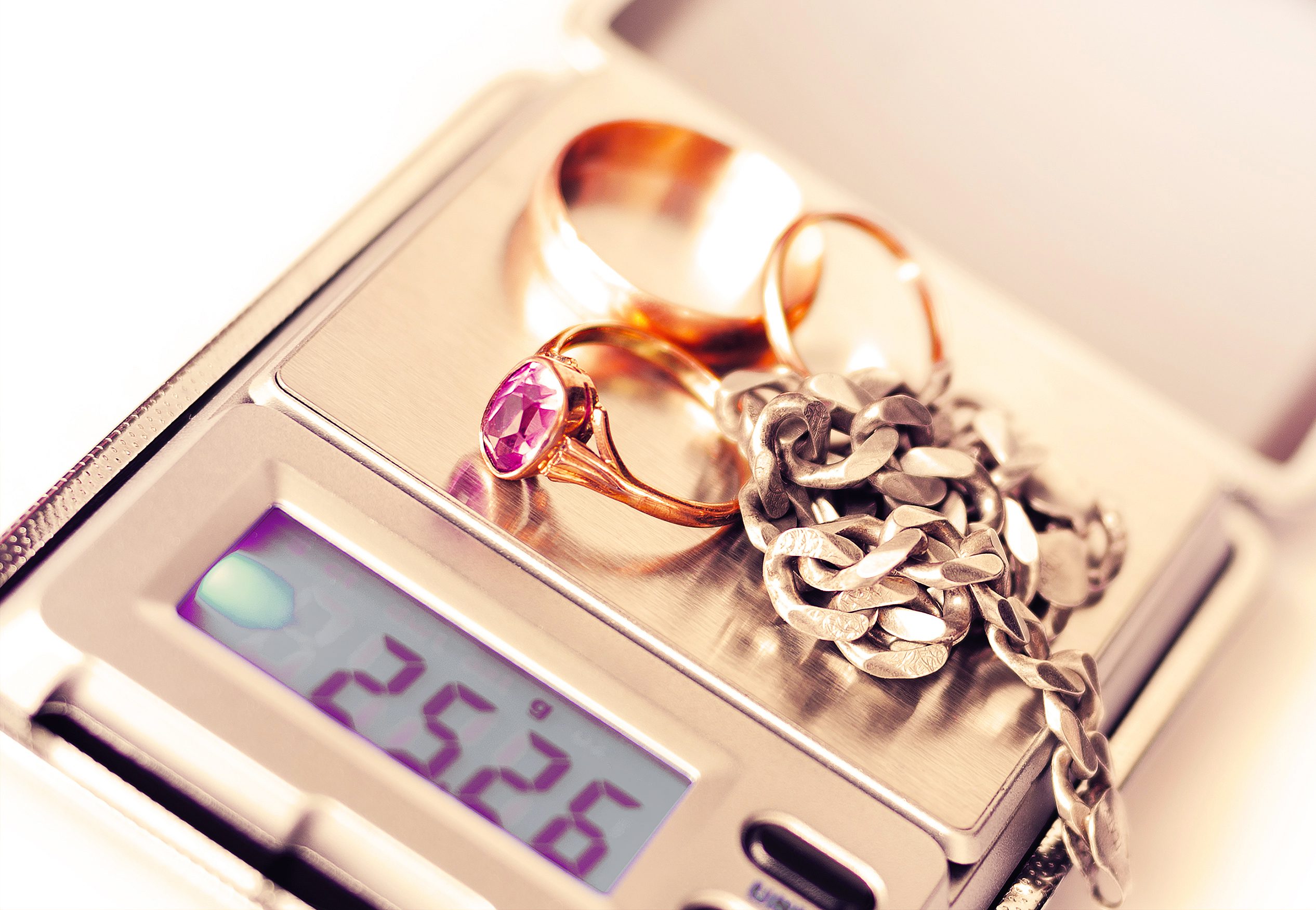 Gold rings and silver chain being weighed at Ideal Jewelry and Loan pawn shop.