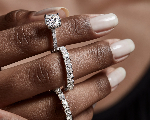 Close-up of a hand wearing a diamond engagement ring and tennis bracelet.