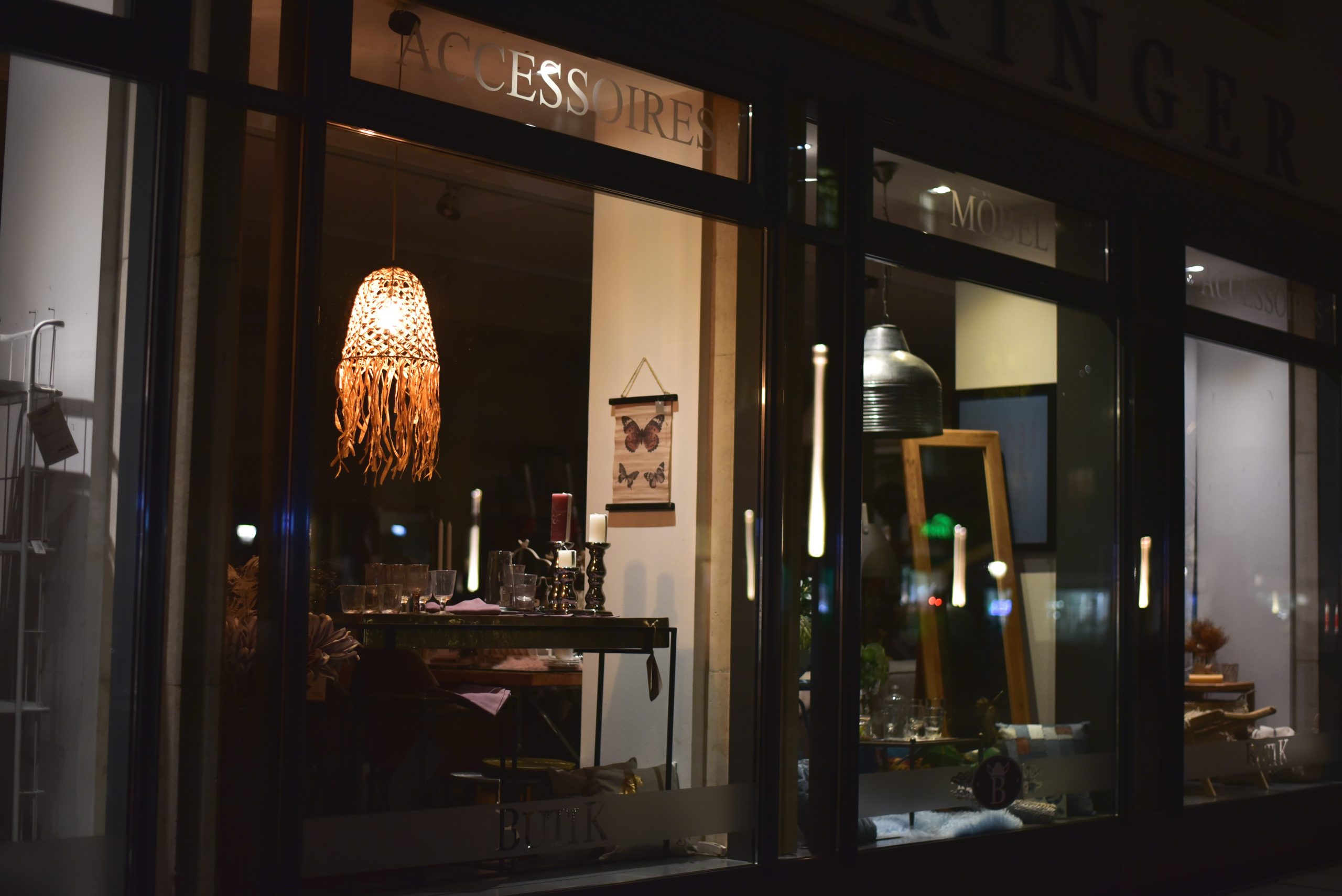 Elegant pawn shop storefront at night with decorative lighting and interior accessories visible through the window