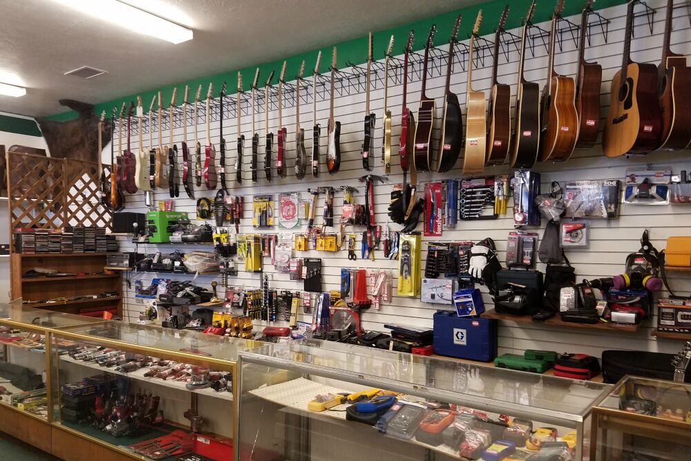 Pawn shop interior displaying guitars, power tools, electronics, and accessories for pawn loan eligibility