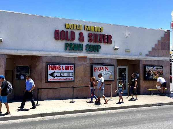 People walking past the world-famous Gold & Silver Pawn Shop storefront on a sunny day