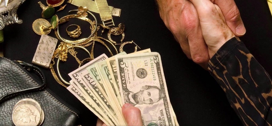 Handshake over cash and jewelry during a pawnshop transaction