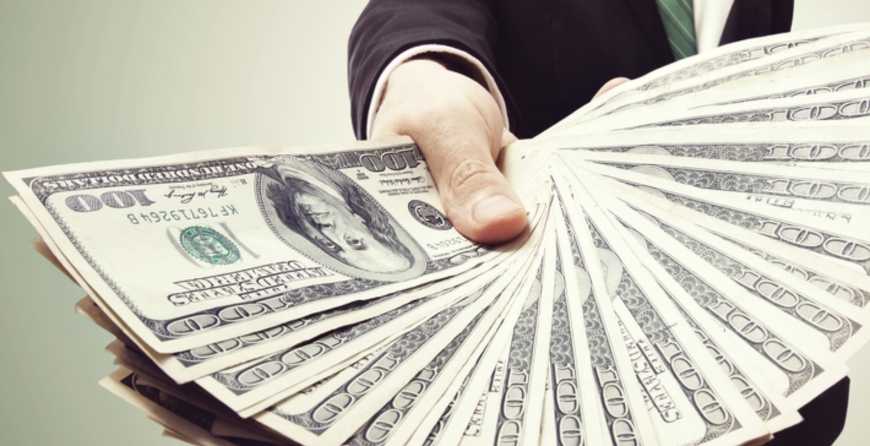 Person handing out a large stack of hundred‑dollar bills symbolizing quick cash