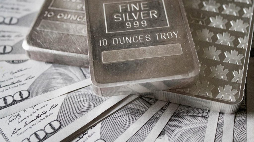 Silver bars displayed over hundred-dollar bills symbolizing cash for silver