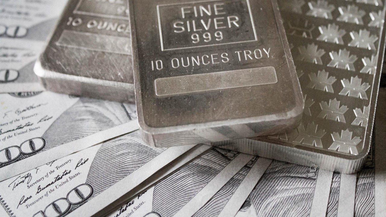 Silver bars displayed over hundred-dollar bills symbolizing cash for silver