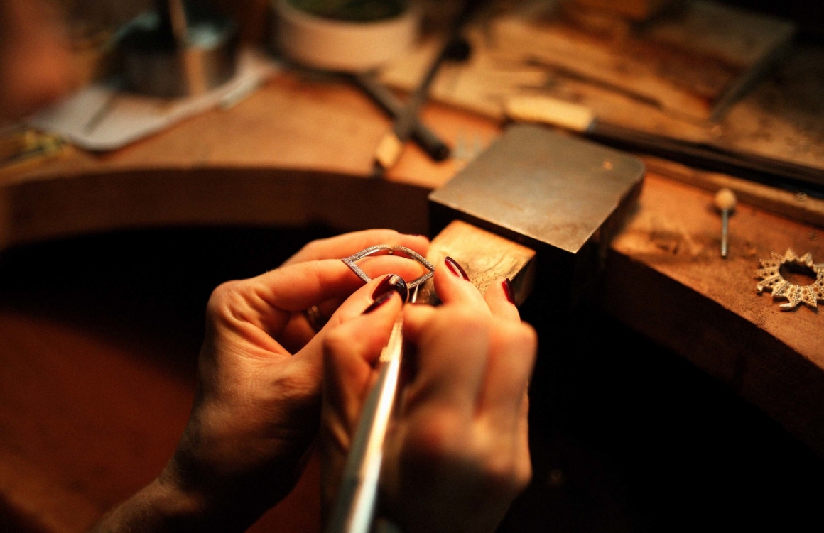 Jeweler carefully repairing a delicate piece of jewelry on a wooden workbench