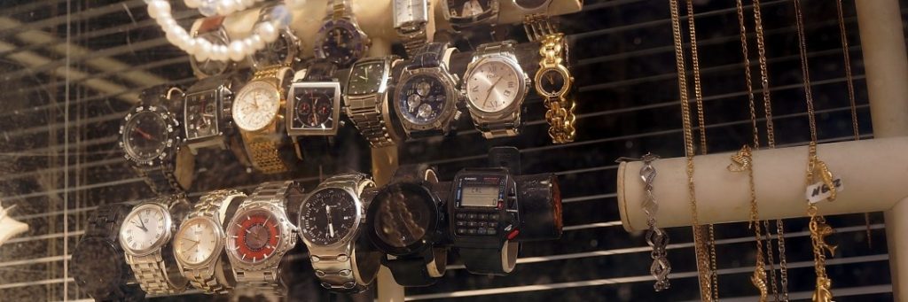 Display of assorted wristwatches and jewelry in a pawn shop window