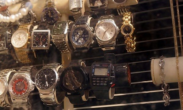 Display of assorted wristwatches and jewelry in a pawn shop window