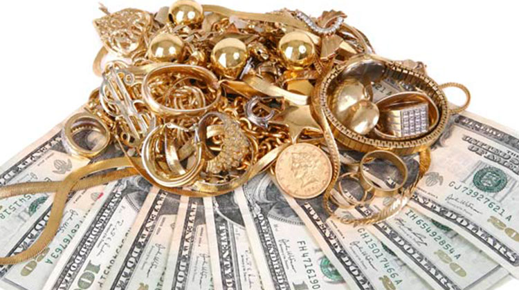 Pile of gold jewelry and coins on top of US dollar bills