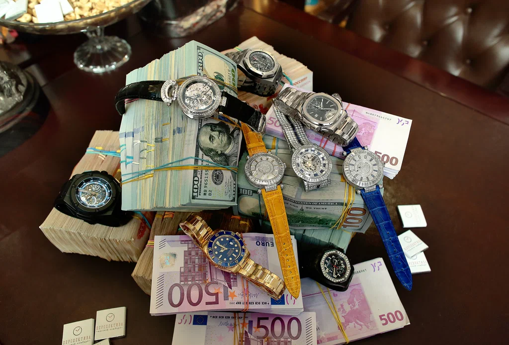 Luxury items including a watch, gold jewelry, and camera in a pawnshop display