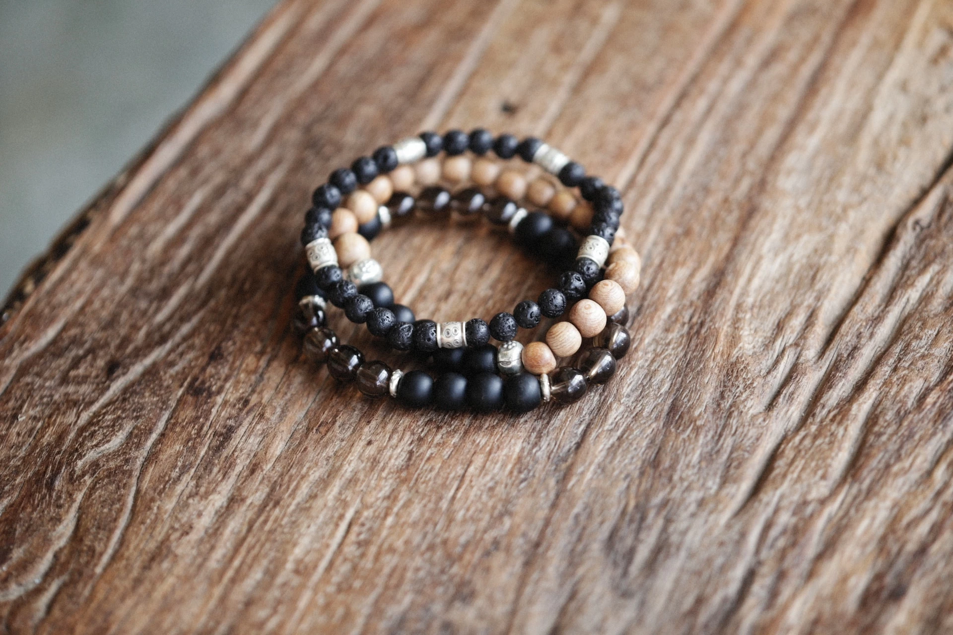 Handmade beaded bracelets with wood and black stones on a rustic wooden surface
