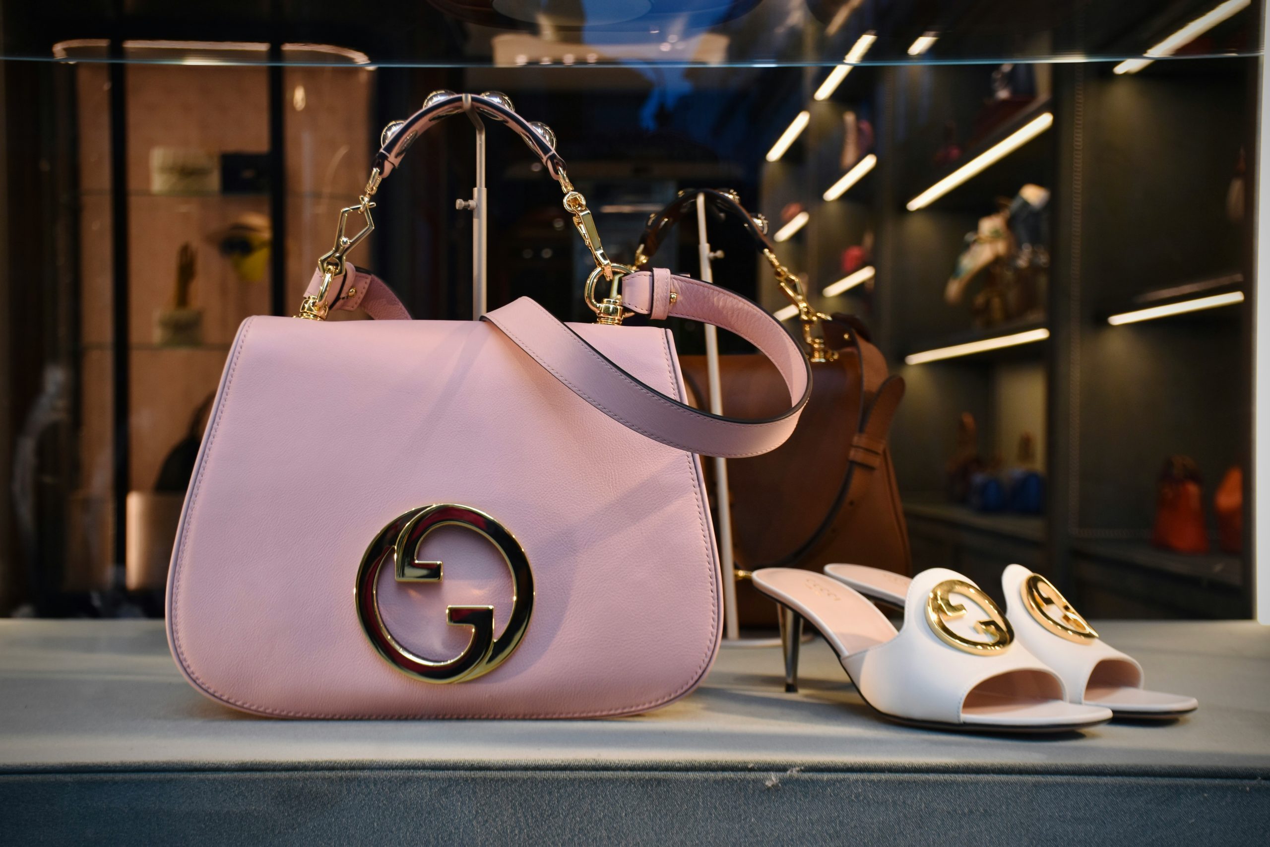Pink Gucci handbag and white Gucci heels displayed in a luxury boutique window