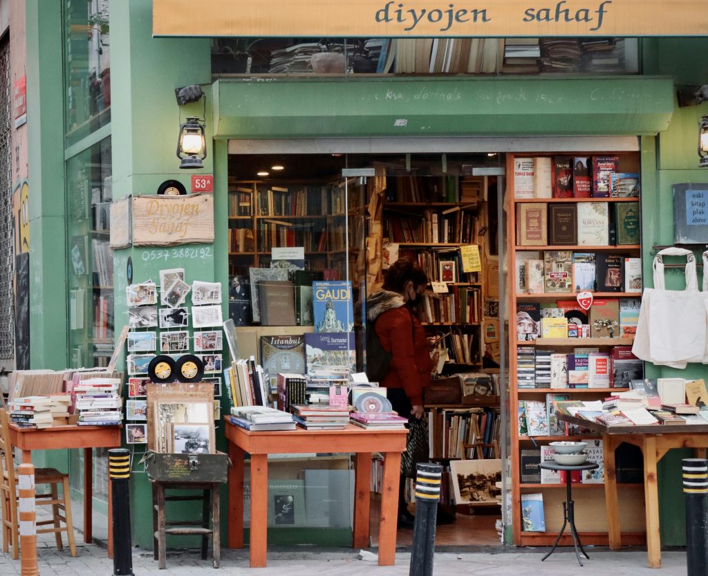 A vintage bookstore storefront with tables of old books and postcards, evoking classic pawn shop charm
