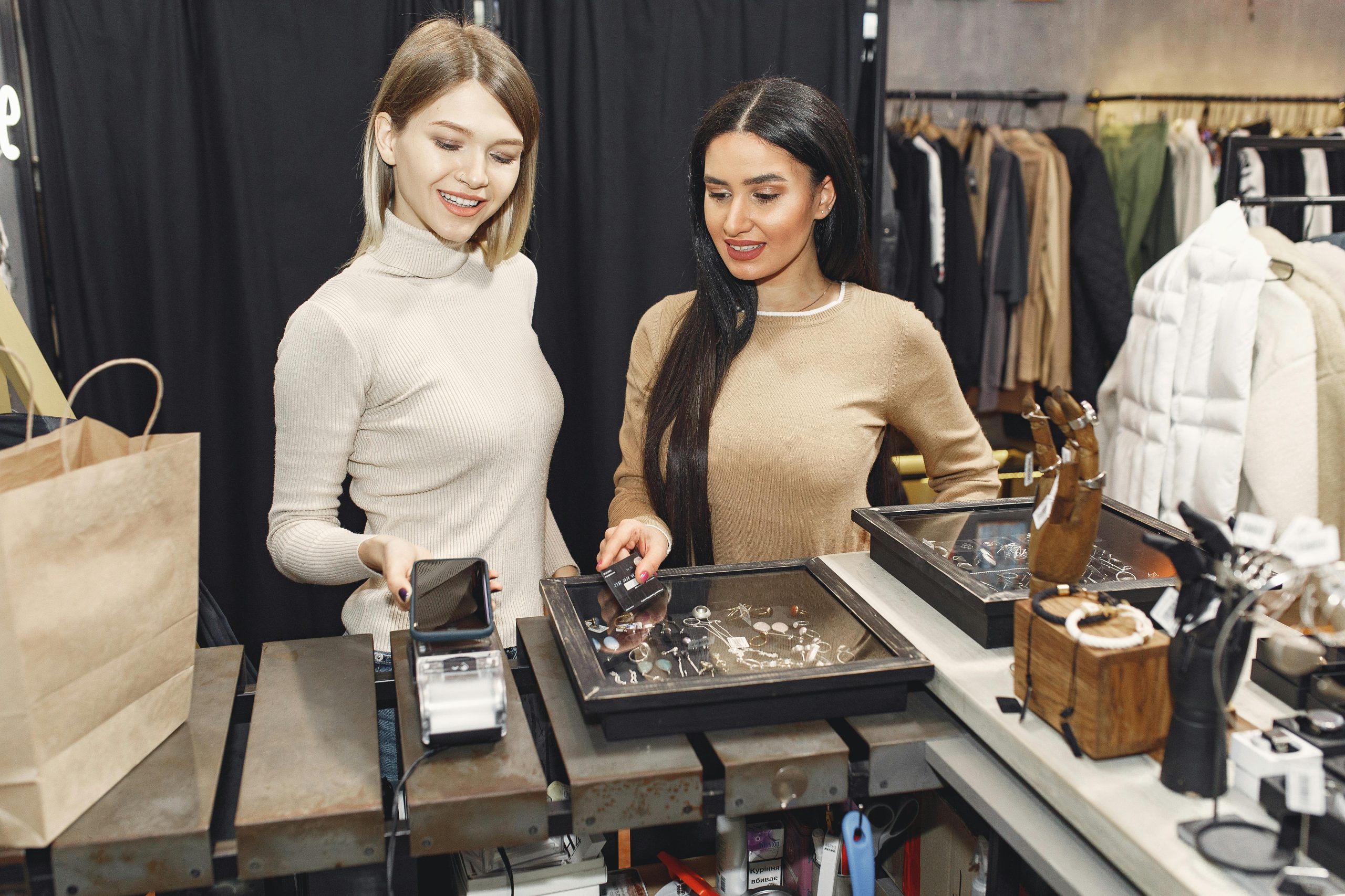 Two women smiling while shopping for jewelry at a pawn shop counter