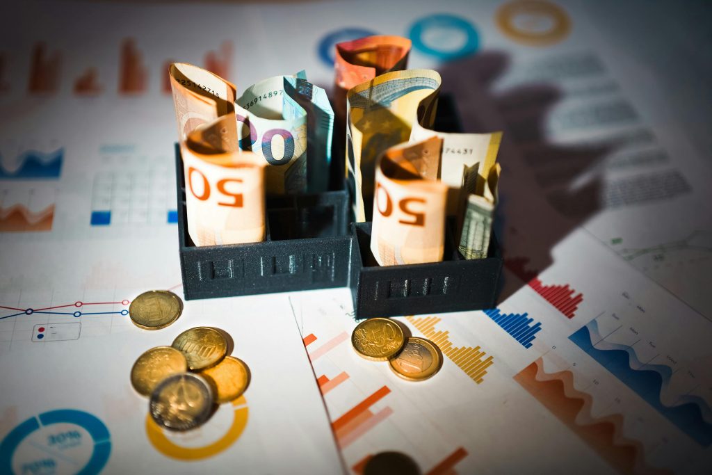 Rolled euro banknotes and coins placed on colorful financial charts