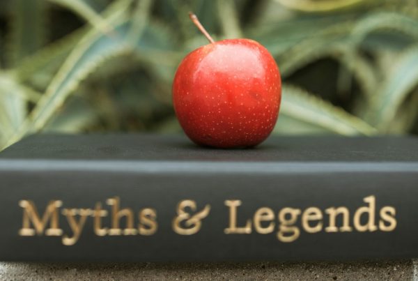 A red apple resting on a book titled "Myths & Legends," symbolizing common misconceptions about pawn shops